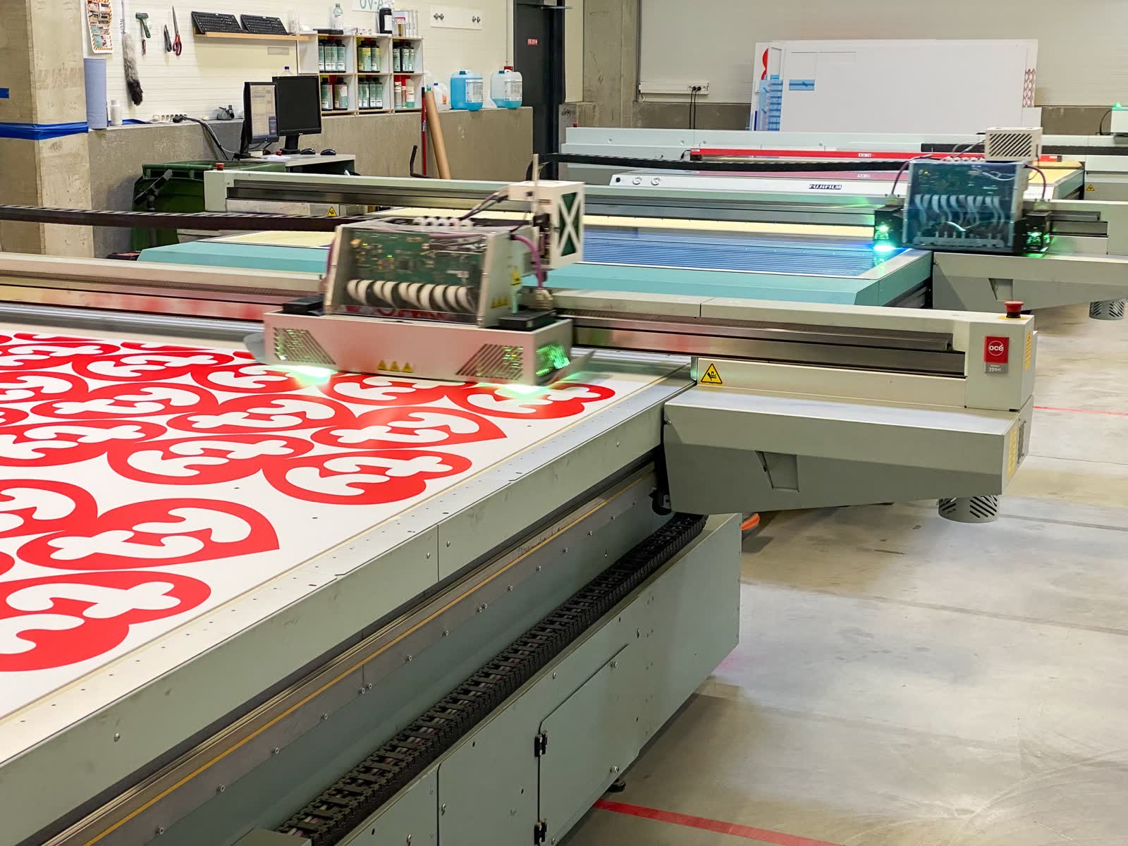 Large-format UV flatbed printer printing a red pattern.