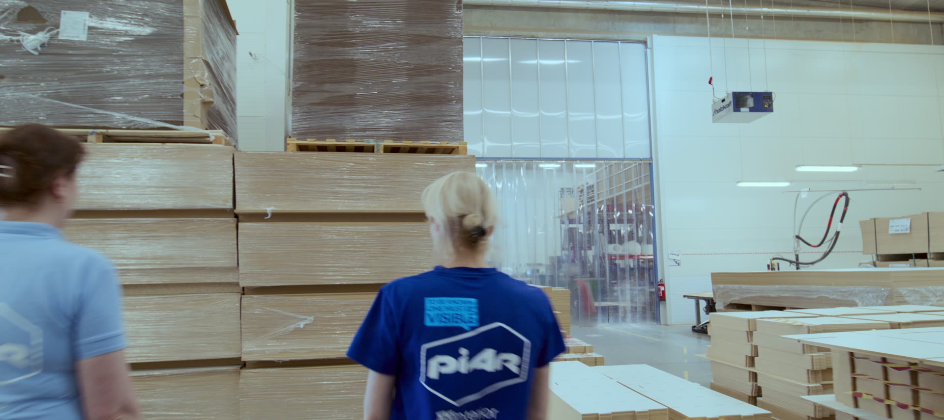 Piar team in blue Piar T-shirts walking through the factory between stacks of flat-packed board.
